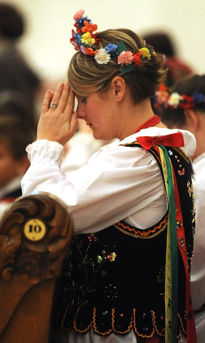 Jill Loos, of Sloan, a member of the Polish Heritage Dancers of Western New York prays after receiving communion during a mass celebrating 1,050 years of Polish commitment to the Catholic faith at St Joseph Cathedral in Downtown Buffalo. (Photo by Dan Cap